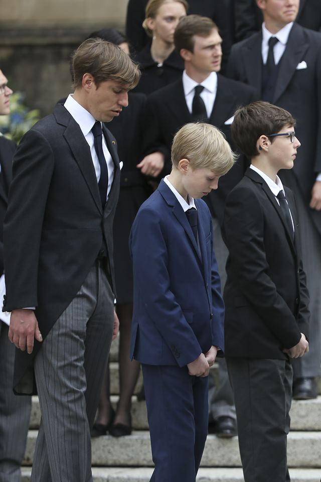 Homem ao lado de dois meninos. Todos vestidos com terno