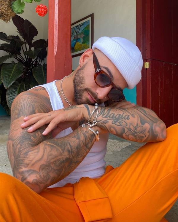 Na imagem com cor, o cantor Maluma usa blusa regata branca 