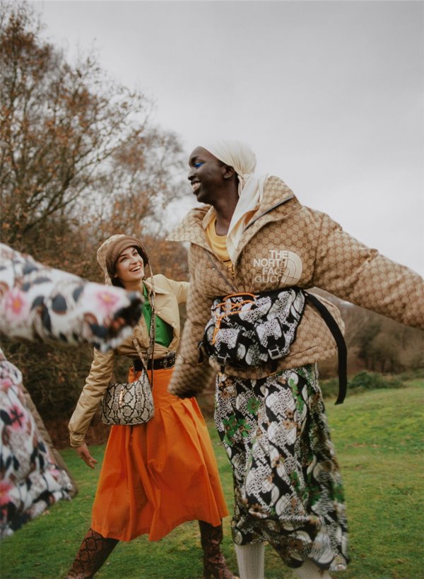 Modelos vestindo roupas da Gucci com a North Face. A primeira mulher é branca e está usando uma saia laranja. A segunda é uma mulher negra que usa casaco de estampa de onça.