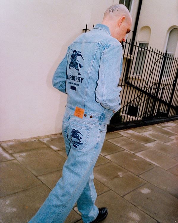 Homem branco usando peças jeans andando na rua 