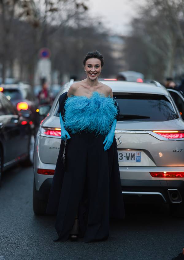 Mulher usa look azul com plumas e luvas