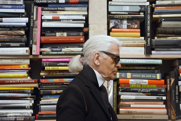 O estilista da Chanel, Karl Lagerfeld, morto em 2019, em sua biblioteca em Paris, França. Ele usa blazer preto, camisa branca e óculos escuros - Metrópoles