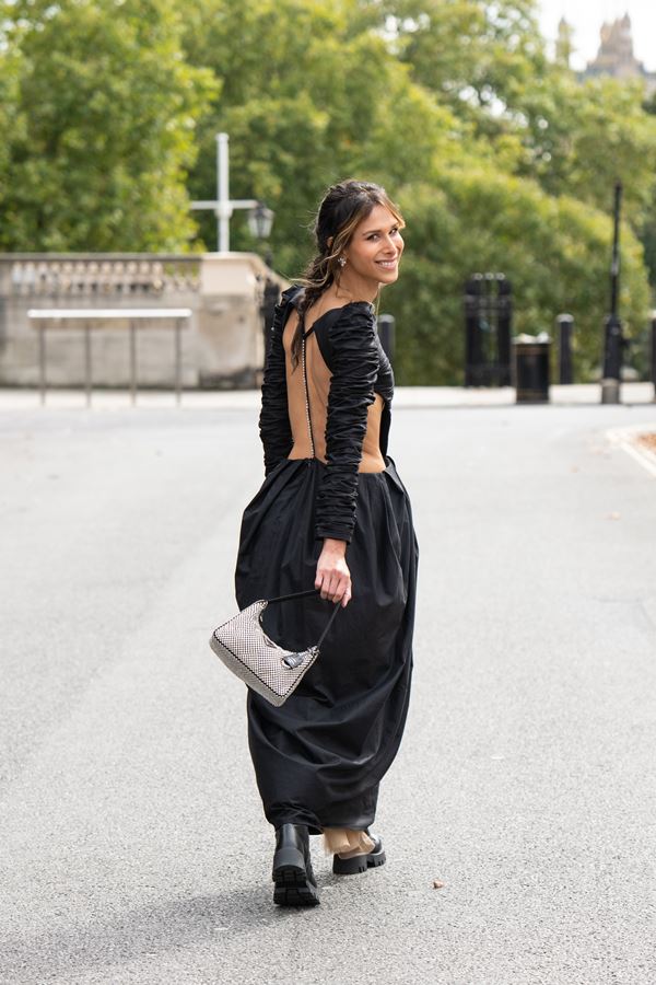 Mulher branca com vestido preto andando na rua