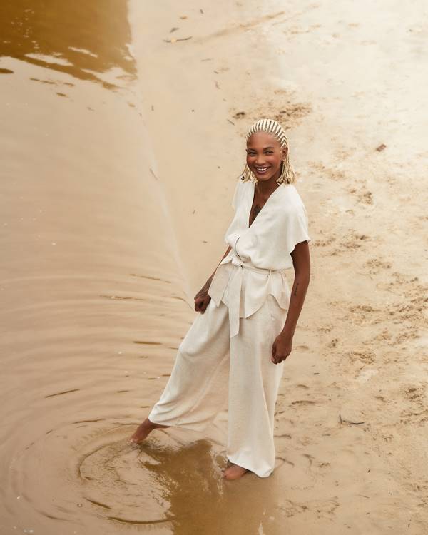 Mulher com look branco e pés na areia