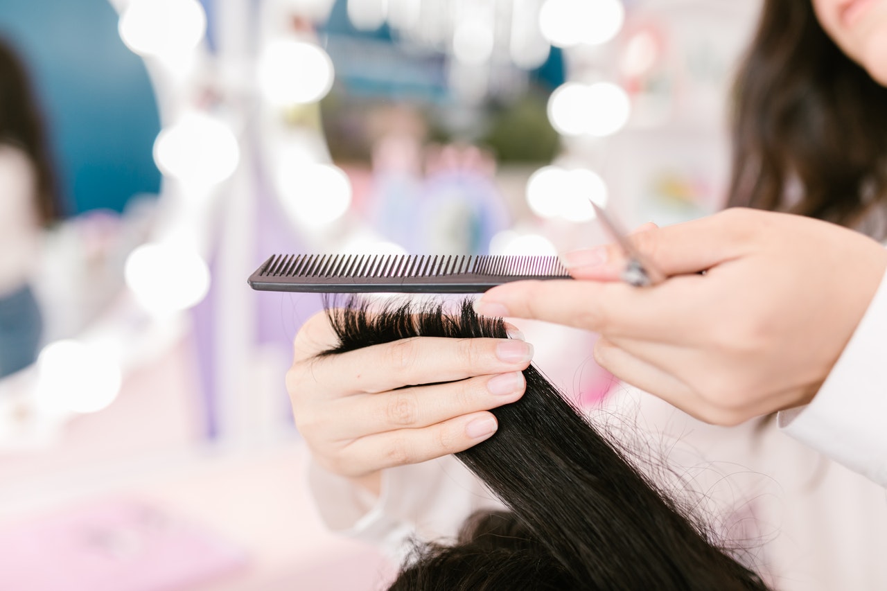 Dedos cortando o cabelo de mulher