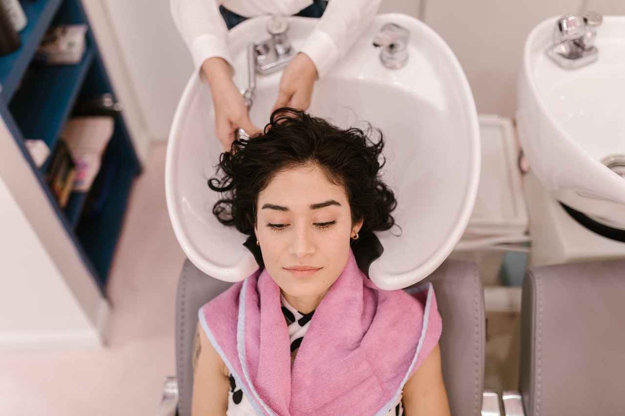 Profissional lavando o cabelo de cliente em salão de beleza