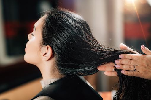 mulher passando produto no cabelo