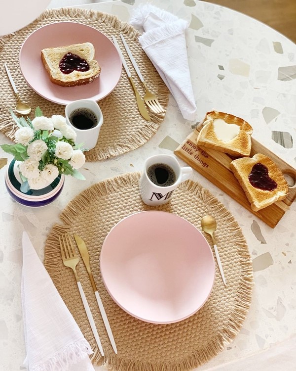 Mesa de café da manhã posta com pratos, canecas e torradas