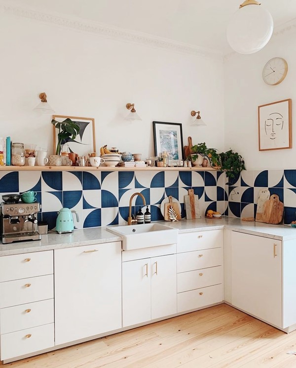 Cozinha moderna e minimalista. Na foto é possível ver azulejos brancos e pretos geométricos, uma pia e armários