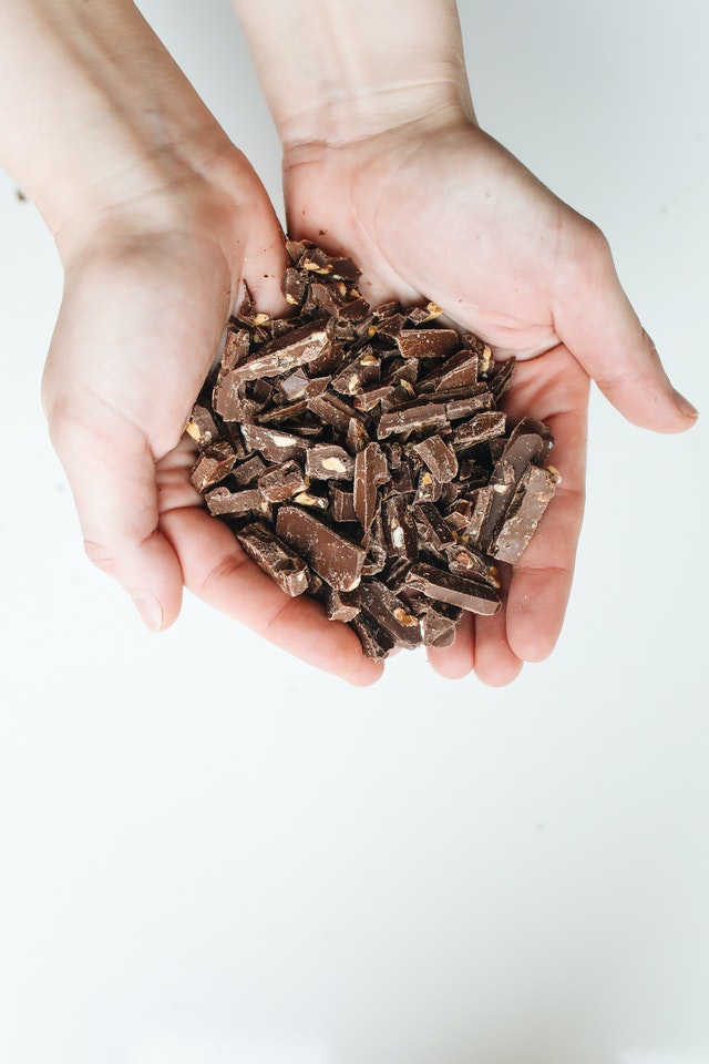 Mãos segurando pedaços de chocolate