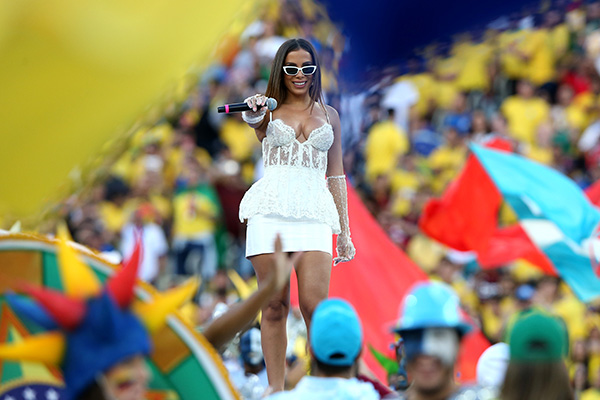 Cantora Anitta cantando no encerramento da Copa America, em 2019, no Brasil. Ela usa um corset de renda branca, com saia justa, também na cor branca.