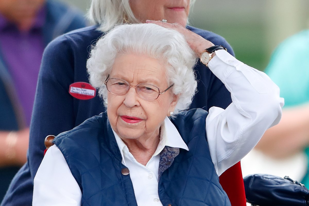 Foto colorida. Rainha Elizabeth pegando no cabelo