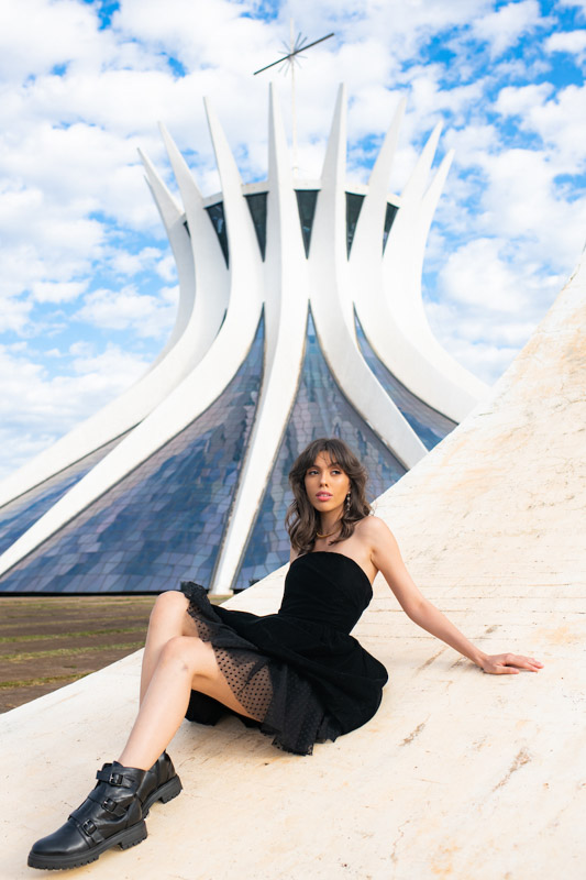 Modelo de cabelo médio e franja usa vestido preto com volume e coturno