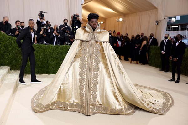 Rapper Lil Nas X com uma capa dourada, com cauda gigante, no tapete vermelho do evento Met Gala