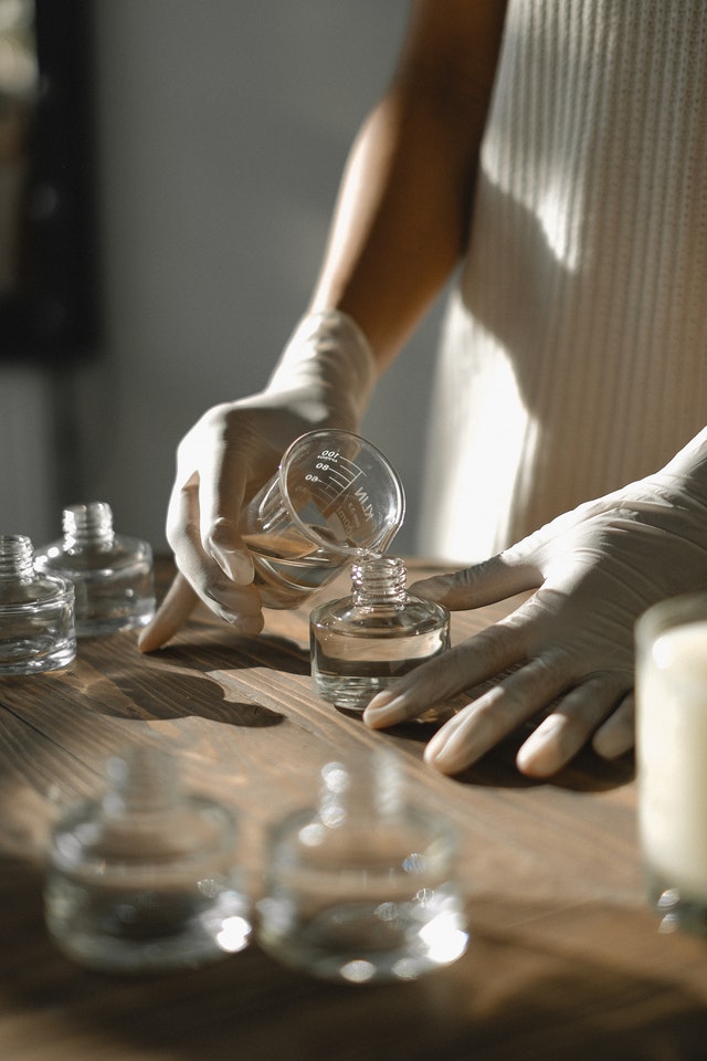 Mãos despejando perfume em frasco