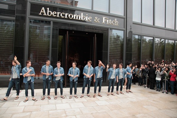 Na imagem com cor, homens posam em frente a loja da Abercrombie