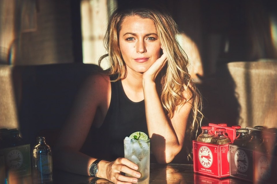 Foto colorida. Blake Lively com um drinque