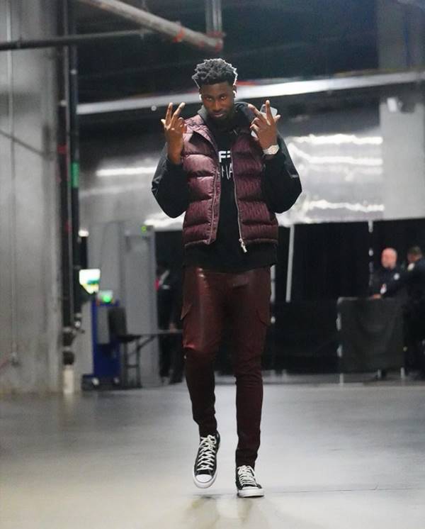 Jogador de basquete usa camiseta preta, colete puffer e calça marrom