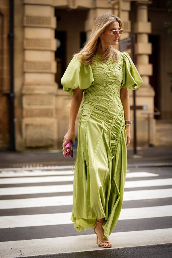 No street style, mulher loira usa vestido verde com mangas curtas bufantes e drapeados frontais