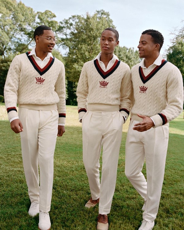 Três homens negros, carecas, posando para foto em campanha da Ralph Lauren. Eles usam a mesma roupa, que parece ser o uniforme da faculdade: uma camisa polo branca e um suéter bege com calça de alfaiataria da mesma cor.