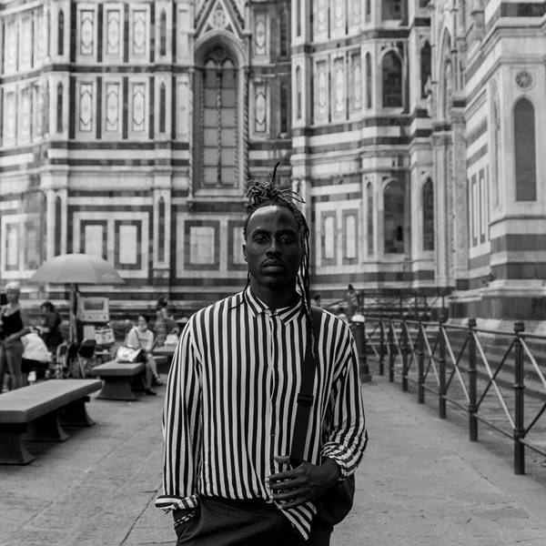 Homem em fotografia preto e branco usa camisa listrada 