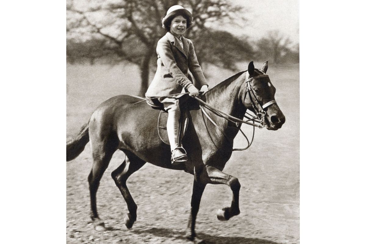 Foto em preto e branco. Rainha Elizabeth em um cavalo