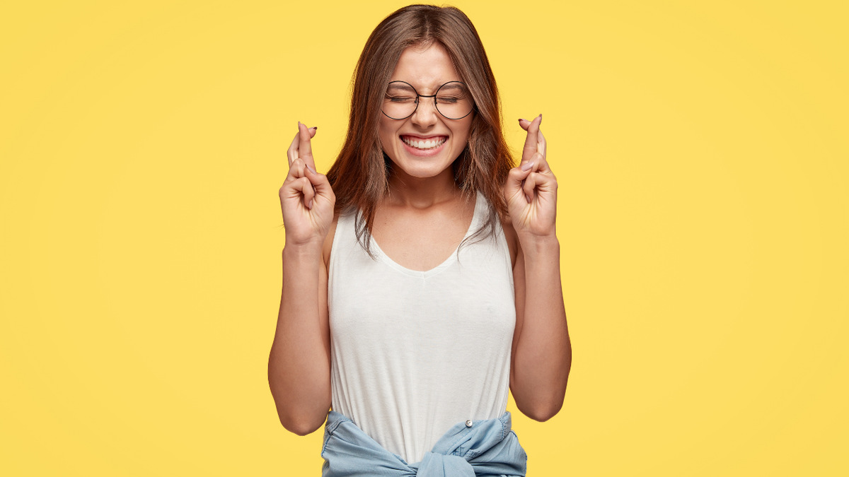 Foto colorida menina cruzando os dedos