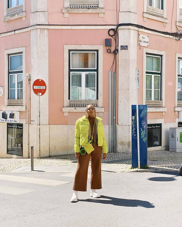 mulher usa calça marrom, casaco verde e bolsa verde do mesmo tom