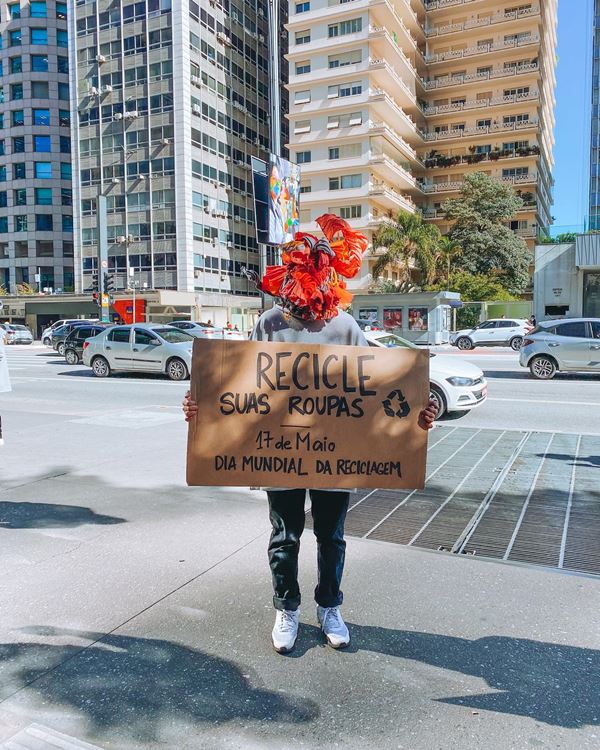 Pessoa andando na rua com uma placa de papelão em que reivindica por sustentabilidade