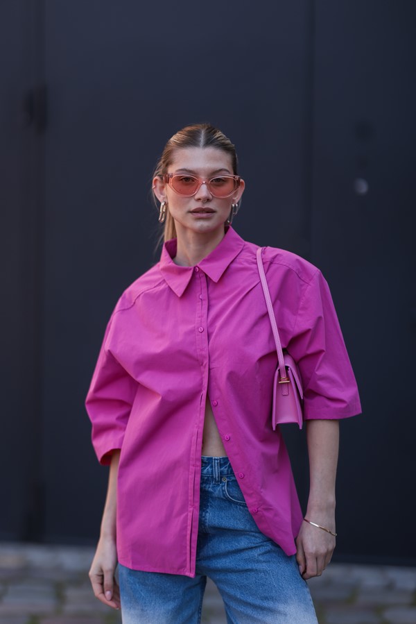 Mulher branca com camisa social andando na rua 