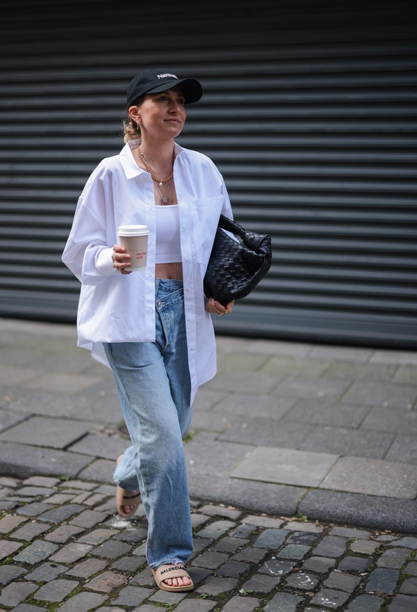 Mulher branca com camisa social andando na rua 