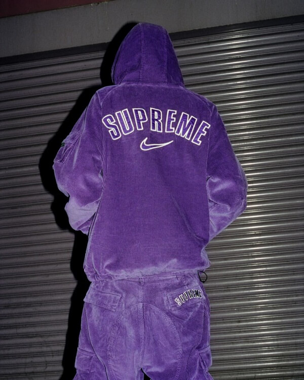 Na imagem com cor, modelo usa conjunto roxo da Nike e Supreme