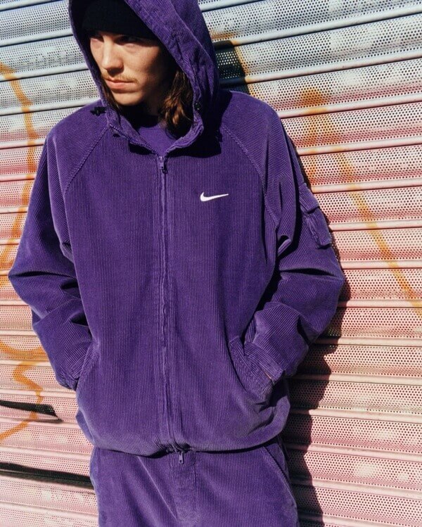 Na imagem com cor, modelo usa conjunto roxo da Nike e Supreme