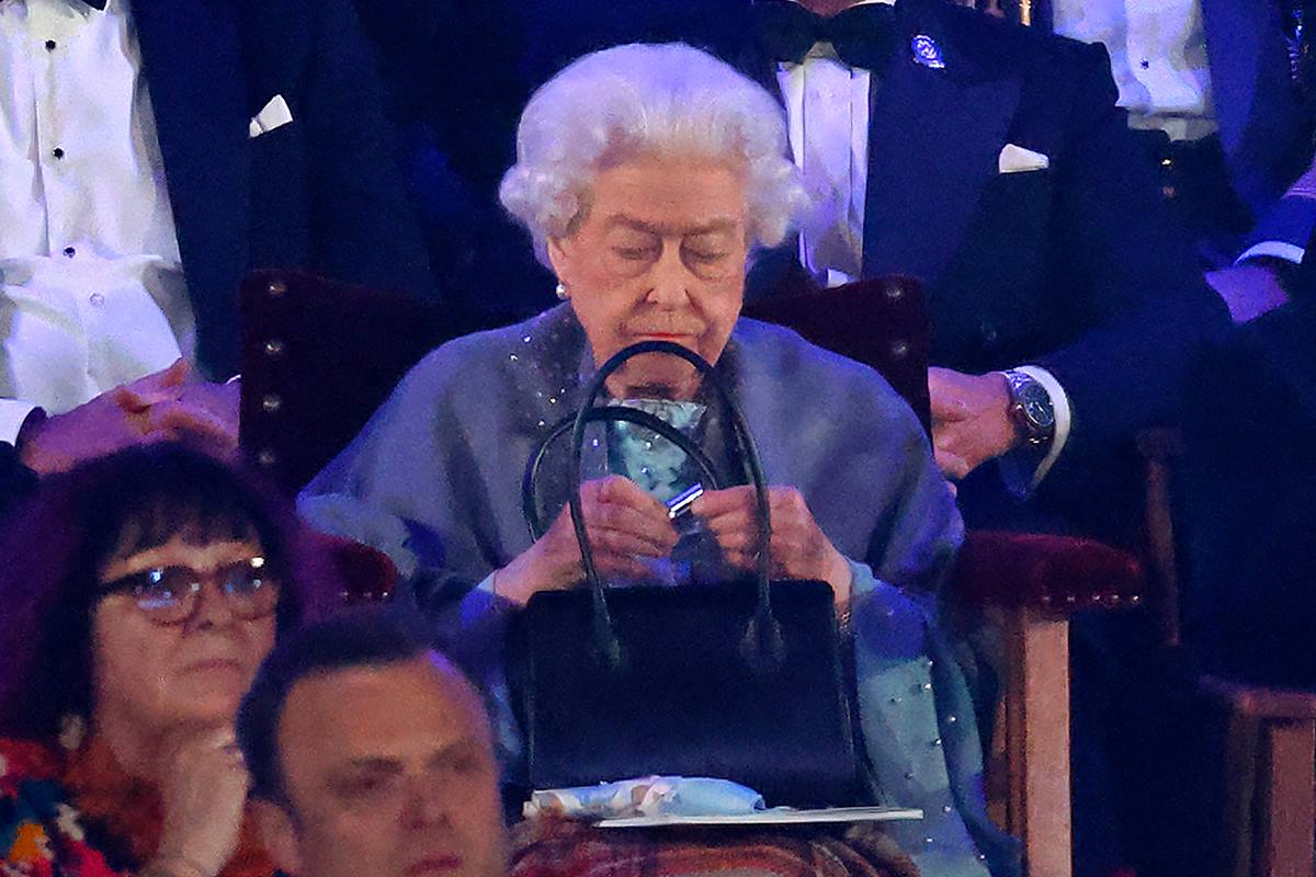 Foto colorida. Rainha Elizabeth retoca o batom