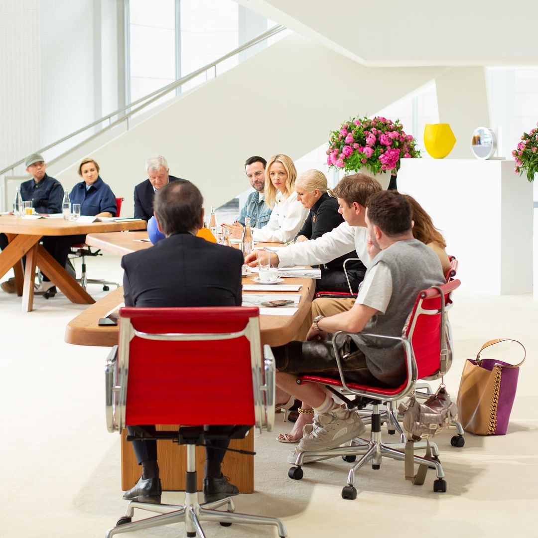 Na imagem com cor, grupo de pessoas, homens e mulheres, sentados à mesa