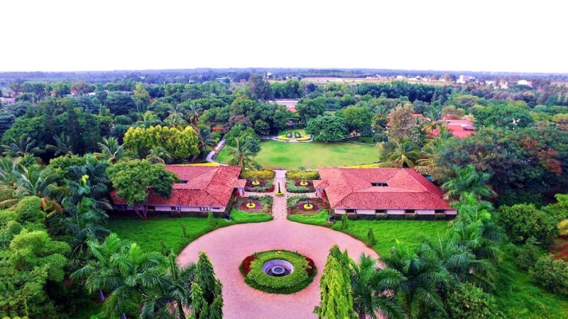 fotografia colorida de imagem aérea de fazenda indiana com dois prédios e uma praça no centro