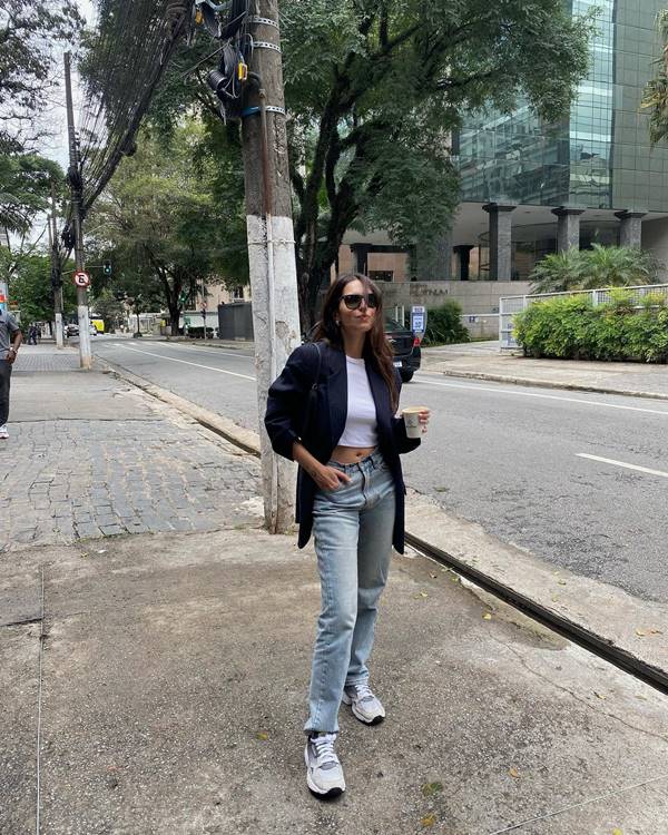 Mulher com calça jeans, tênis e blazer preto