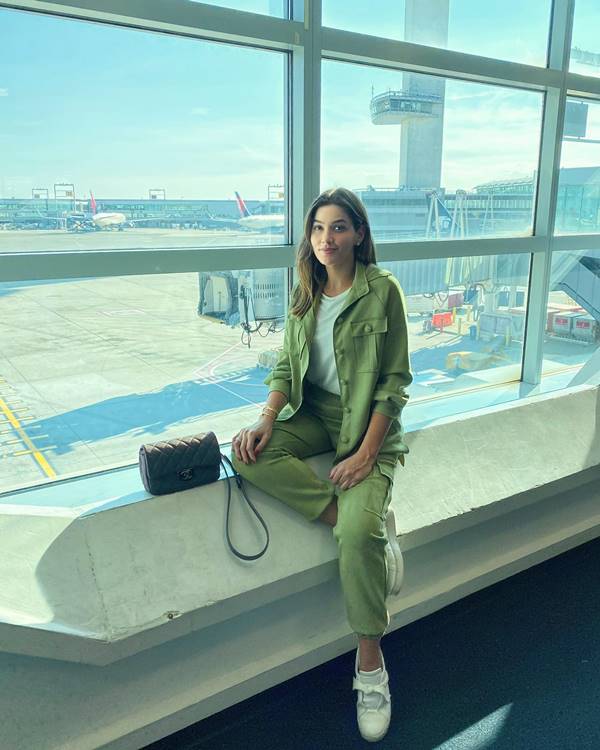 Mulher branca e loira no aeroporto com look verde