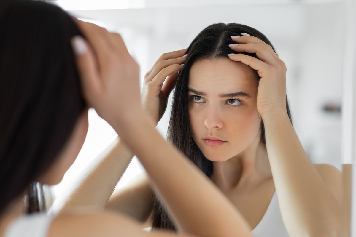 Mulher olhando o couro cabeludo no espelho