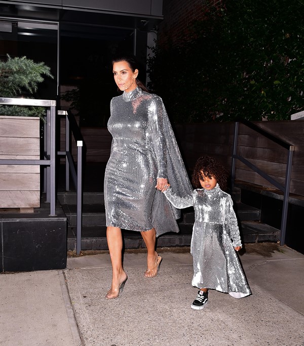 Na imagem com cor, Kim Kardashian usa vestido prateado combinado com a filha