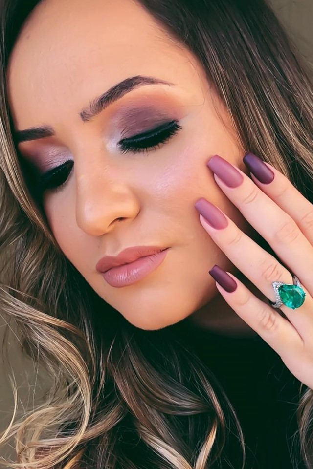 Foto colorida. Mulher parda de cabelo longo. Ela mostra as unhas