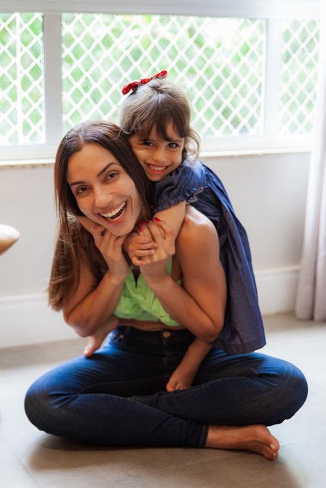 Foto colorida. Mulher e menina abraçadas