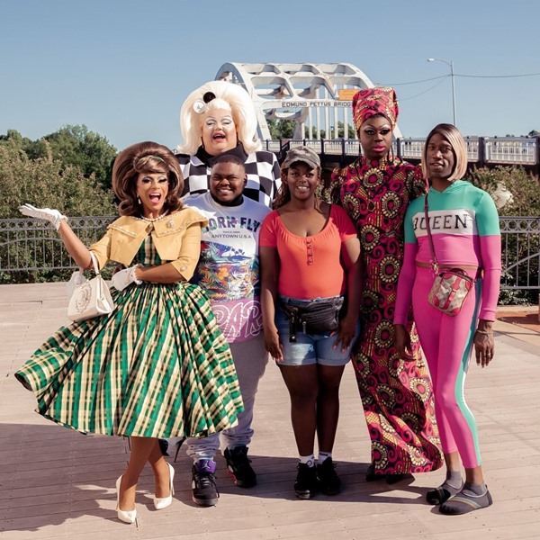 Três drag queens participantes da série We're Here, da HBO. Na foto, as três aparecem com roupas extravagantes e com outras pessoas não montadas de drags