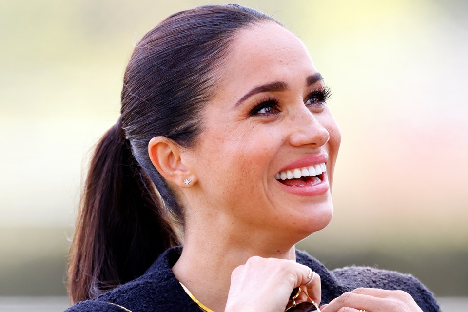 Foto colorida. Mulher com um rabo de cavalo e sorridente