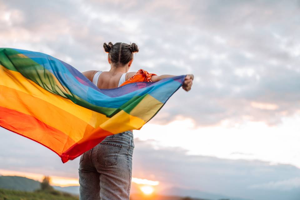 Foto colorida de mulher com bandeira do orgulho LGBT
