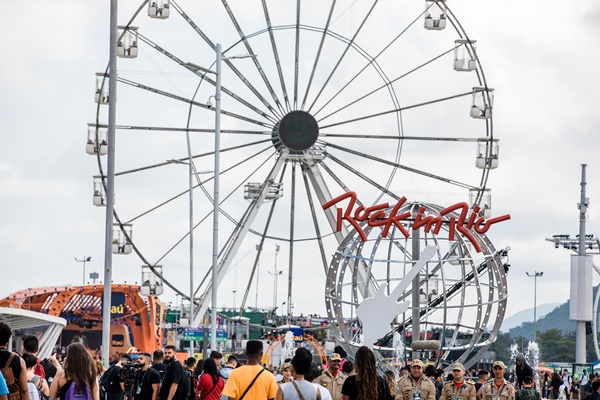 Multidão de pessoas andando na cidade do Rock, no Rock in Rio, perto da roda gigante do evento