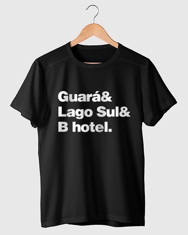 Camiseta preta, em um fundo branco e pendurada em um cabide de madeira, com as palavras Guará, Lago Sul e B Hotel escritas em branco