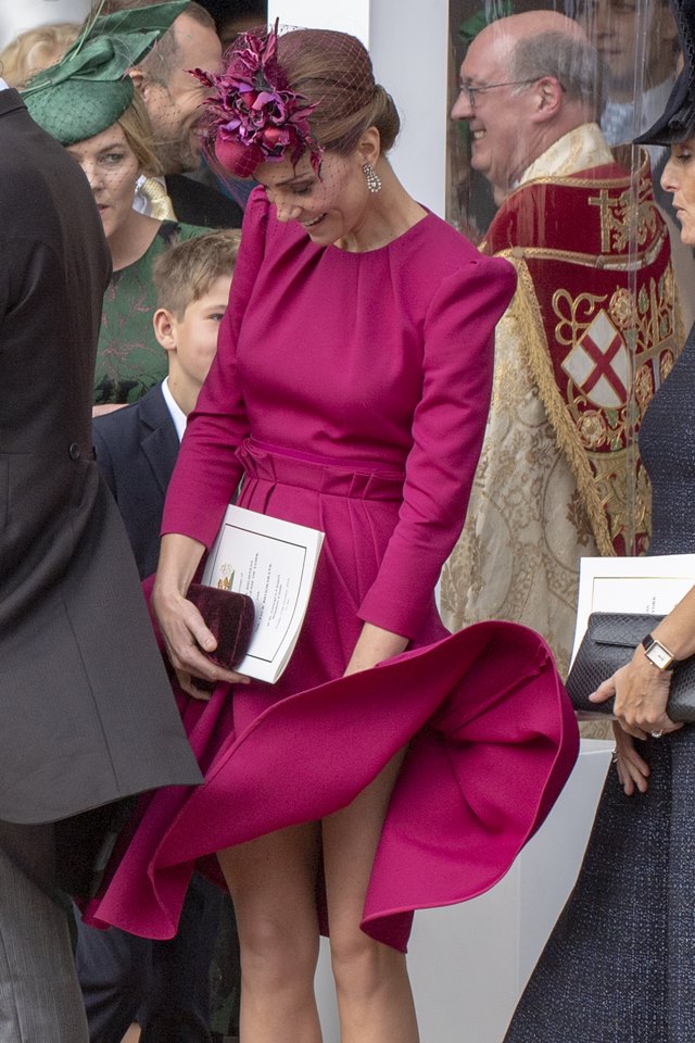 Foto colorida. Mulher com vestido rosa. A peça levanta com o vento