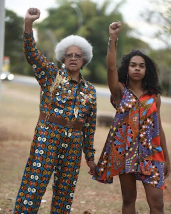 Mulheres negras com mãos para cima, fazendo símbolo de resistência, usando looks da marca Diáspora 009