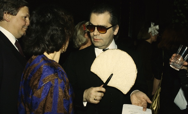 O estilista Karl Lagerfeld, em 1982, usando um terno clássico preto e branco e óculos escuros